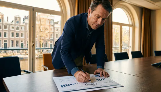 Zakenvrouw bestudeert dashboard-uitdraai met omcirkelde klanttevredenheidsscore aan vergadertafel in Amsterdams kantoor.