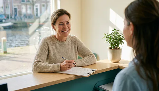 Tevreden klant vult feedbackformulier in op klembord bij moderne receptie in Amsterdam, omringd door zacht natuurlijk licht en tealgroene tinten.